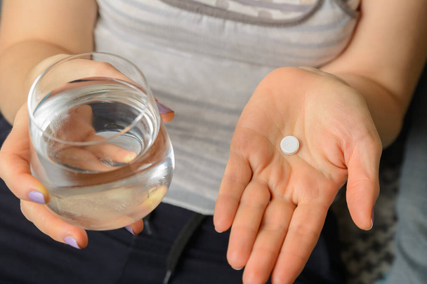Tabletki medyczne są umieszczone w dłoni, a szklanka wody jest w dłoni do umycia. - Zdjęcie, obraz