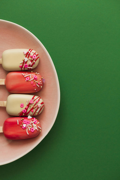 Pink popsicle cakes on a green background - Foto, imagen