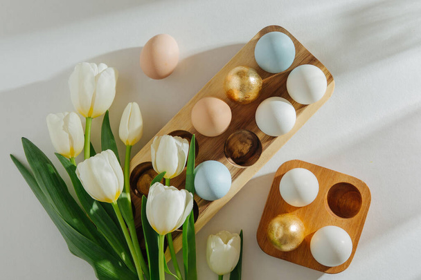 White tulips and Eggs in wooden egg-box with sunlight on white background. Stylish spring Compositions. Easter concept. - Foto, Bild