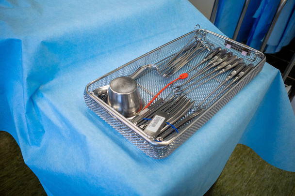 uma peneira de instrumento limpa e desinfetada para realizar uma raspagem do útero está em um pano azul
 - Foto, Imagem