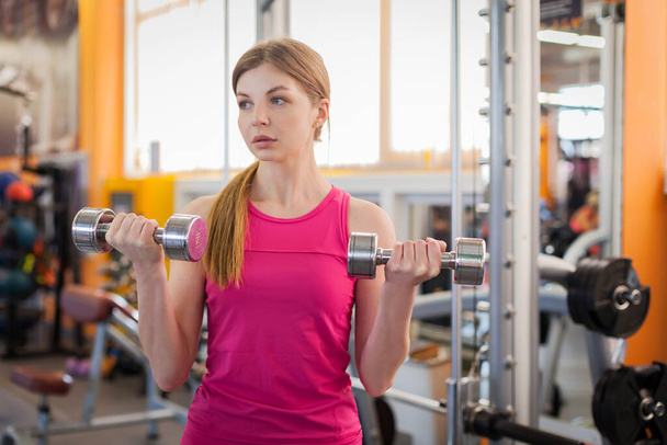Active woman lifting dumbbells in the gym - Fotó, kép