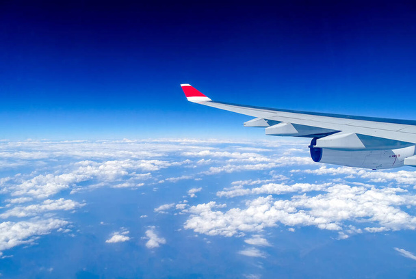 Pilvipeitteen yläpuolella lentävän ilma-aluksen siipi
 - Valokuva, kuva