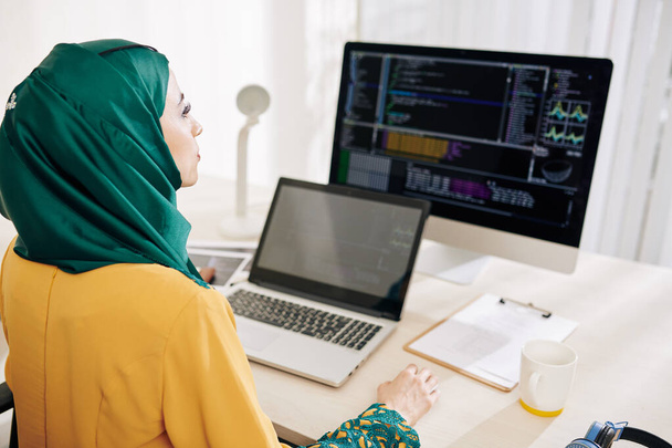 Engenheira de software mulher séria trabalhando em computador e laptop em seu escritório
 - Foto, Imagem