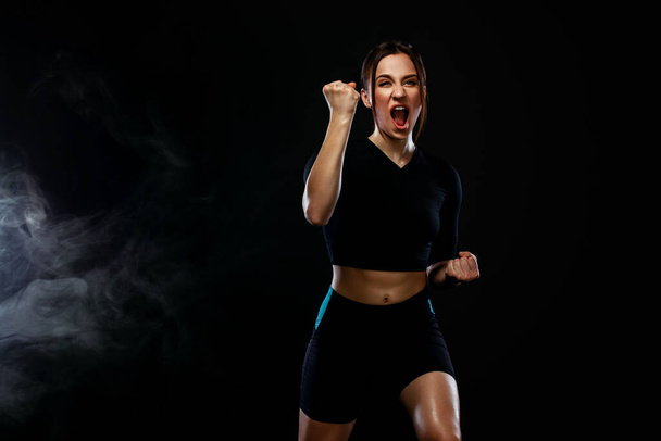 Sprinter and runner girl. Running concept. Woman running on the black background. The concept of a healthy lifestyle and sport. Woman in sportswear. - Zdjęcie, obraz