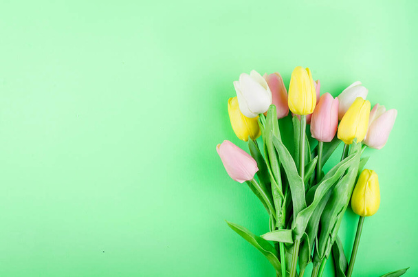 Spring or holiday concept, a bouquet of tulips on green background. March 8, International Women's Day, birthday. Copy space, flat lay, Template mockup greeting card with place for text,  - Фото, изображение
