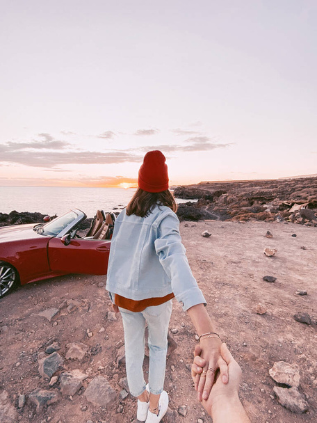 Mujer con sombrero rojo caminando por la costa rocosa
 - Foto, imagen