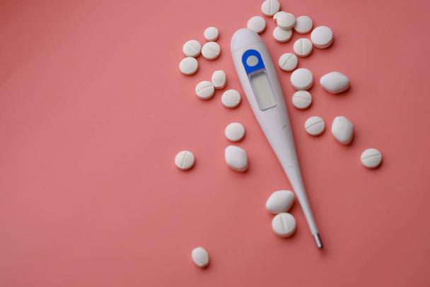 close up of pills and thermometer on pink background  - Foto, Imagem