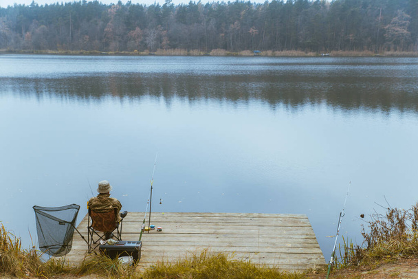 fisherman fishing at calm autumn lake copy space - Фото, зображення