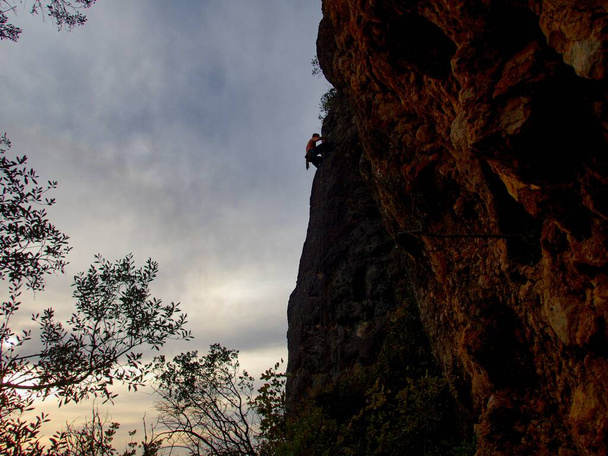 silhouette di uno scalatore su una roccia strapiombante al tramonto
 - Foto, immagini