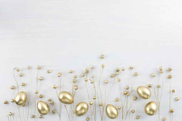 Minimal gold eggs easter concept. Stylish easter golden and black eggs with dried golden flax linum bunch on white wooden background. Flat lay trendy easter. Happy easter card with copy space for text - Fotoğraf, Görsel