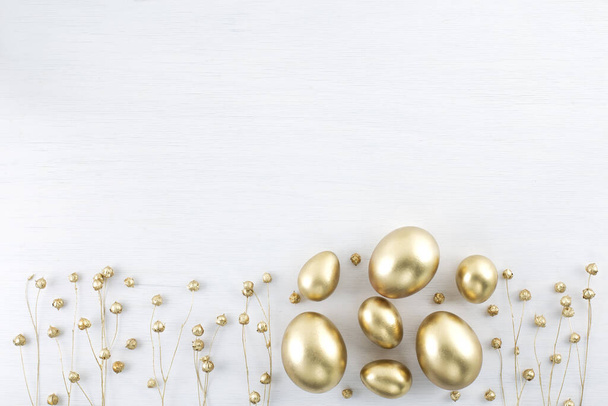 Minimal gold eggs easter concept. Stylish easter golden and black eggs with dried golden flax linum bunch on white wooden background. Flat lay trendy easter. Happy easter card with copy space for text - Φωτογραφία, εικόνα
