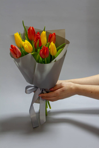 Girls hands hold Still life Bouquet of red and yellow tulips, selective focus - Fotó, kép