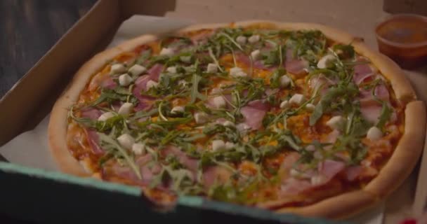 Talentvolle Italiaanse chef-kok serveert een heerlijke traditionele mozzarella pizza bedekt met verse basilicum bladeren op een houten tafel op een bord. Close-up schot op 4k - Video