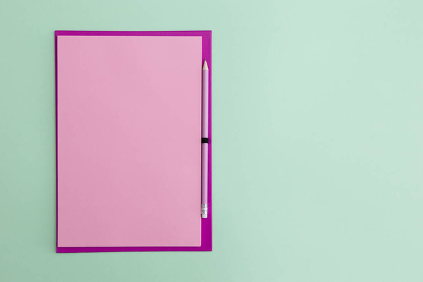 緑の背景にピンクの鉛筆でピンクのノート. - 写真・画像