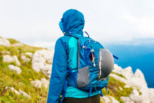 Dziewczyna w niebieskiej kurtce z kapturem i miejskim plecakiem w górach Adygei, Rosja. - Zdjęcie, obraz