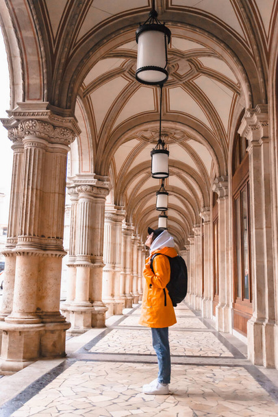 Touristin wandert mit Rucksack in gelbem Regenmantel - Foto, Bild