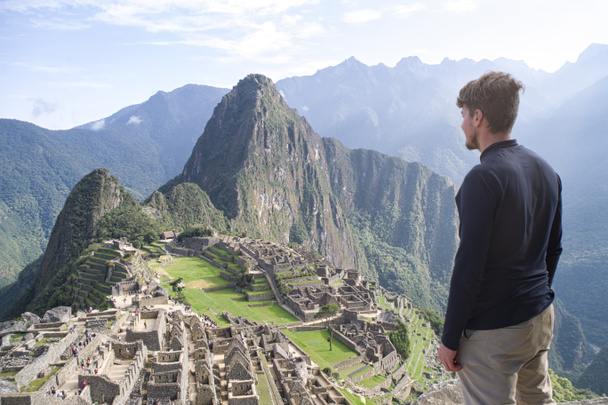 Biały młodzieniec stojący i patrzący na niesamowity krajobraz Machu Picchu. Peru, Ameryka Południowa - Zdjęcie, obraz
