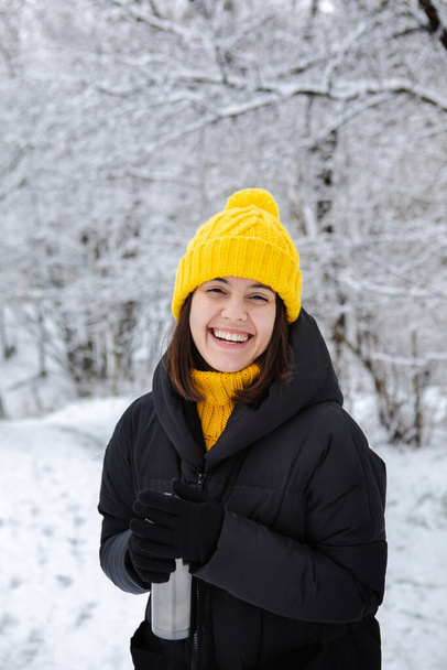 smiling woman in winter outfit drinking warm up drink from refillable mug copy space - Photo, Image