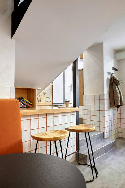 Stílusos. Modern belső tér cafe.Hiteles stílus elemével loft.Kerek fekete-fehér asztalok, székek és narancssárga kanapé.. Fehér csempe narancssárga vonalakkal.Narancs, fehér és szürke színek. - Fotó, kép