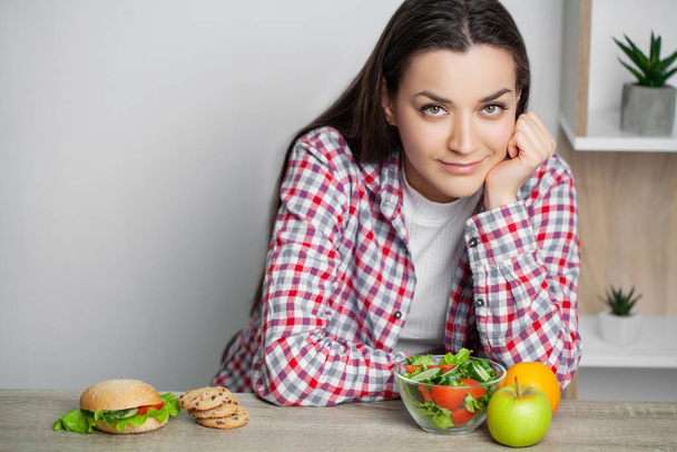 Woman makes a choice between healthy and harmful food - Valokuva, kuva
