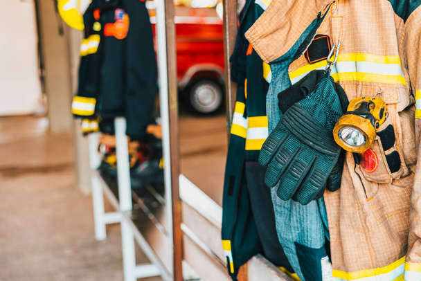 Dettaglio della tuta da lavoro di un vigile del fuoco preparato per l'azione accanto al materiale per spegnere gli incendi in sicurezza. - Foto, immagini