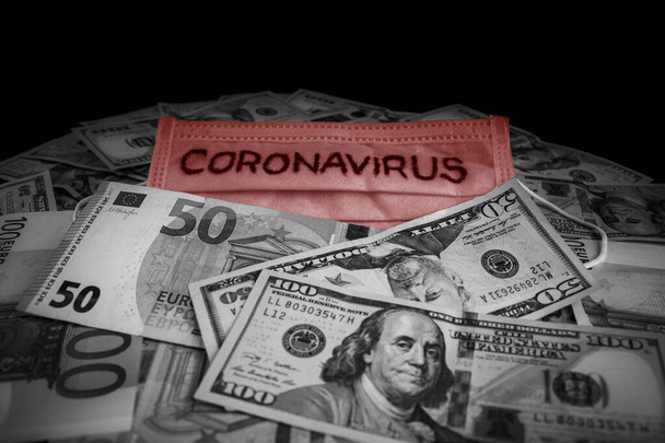 Inscription du coronavirus sur un masque médical au-dessus des billets internationaux. Dollars américains et euros. Coronavirus Avertissement
. - Photo, image