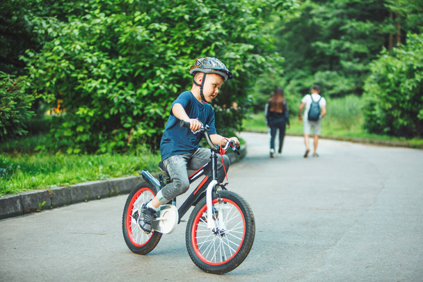 little boy riding on bicycle in helmet in public park - Photo, Image