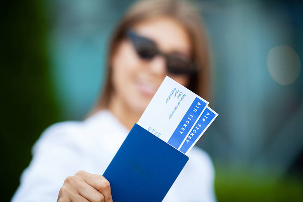 Kobieta posiada bilety lotnicze w pobliżu lotniska w paszporcie. - Zdjęcie, obraz