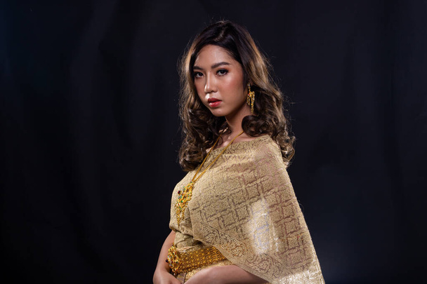 Robe d'or de costume traditionnel thaïlandais ou robe d'or Asie du Sud-Est en femme asiatique avec stand de décoration dans de nombreuses poses sous Studio noir foncé espace de copie de fond avec portrait de fumée
 - Photo, image