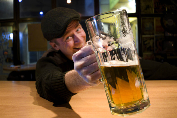 pelirroja casi irlandés chico sentado en el bar y bebe un poco de cerveza y te mira y salud
 - Foto, imagen