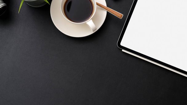 Widok góry ciemnego nowoczesnego miejsca pracy z tabletem makiety, filiżanką kawy i miejsca do kopiowania na czarnym stole  - Zdjęcie, obraz
