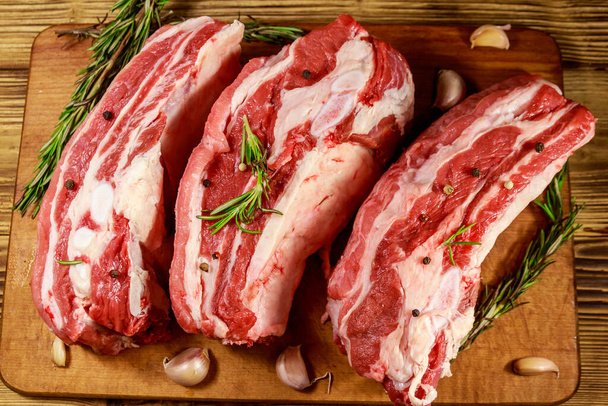 Rauwe varkensribbetjes met specerijen, knoflook en rozemarijn op houten tafel. Top View - Foto, afbeelding