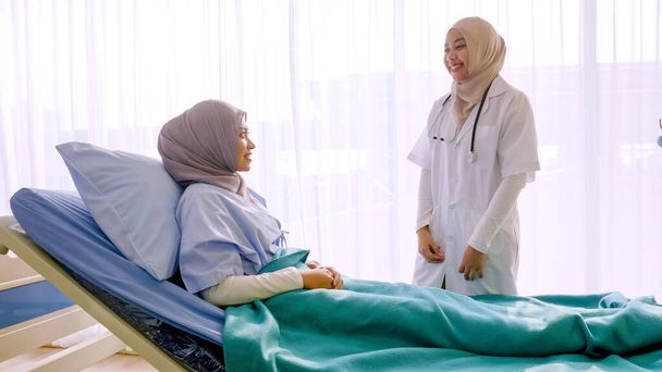 Muslimische Ärztin im Krankenhauszimmer im Gespräch mit Patientin. - Foto, Bild