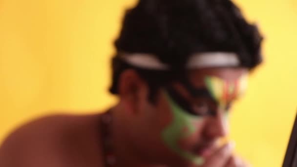 Közelkép egy hagyományos Kathakali táncosról, aki utolsó simításokat végez a sminkjén..  - Felvétel, videó
