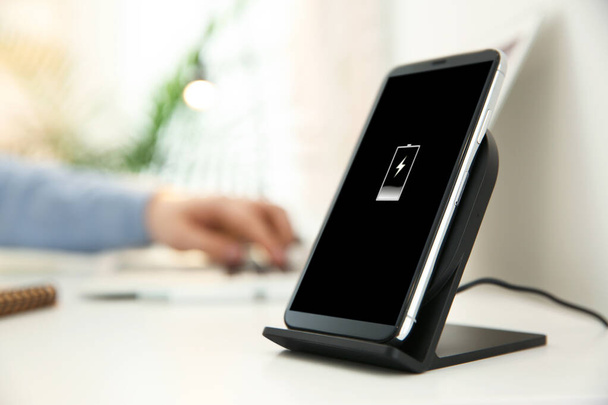 Mobile phone with wireless charger on white table. Modern workplace accessory - Foto, Imagen