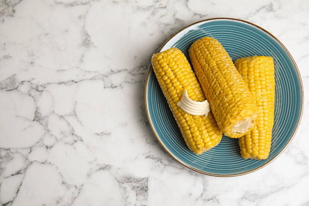 Delicious boiled corn with butter on white marble table, top view. Space for text - Photo, Image