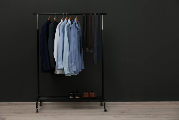 Rack with stylish clothes near black wall - Photo, image