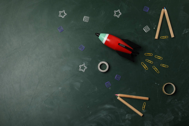 明るいおもちゃのロケットと黒板に学校用品、フラットレイアウト。テキストのスペース - 写真・画像