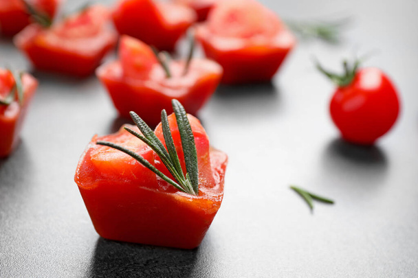 Ice cubes with tomatoes and rosemary on grey table, closeup - Foto, Imagem