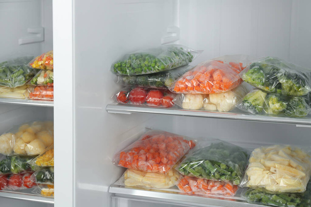 Plastic bags with different frozen vegetables in refrigerator - Fotó, kép