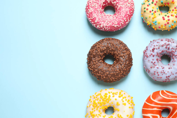 Delicious glazed donuts on light blue background, flat lay. Space for text - Fotó, kép