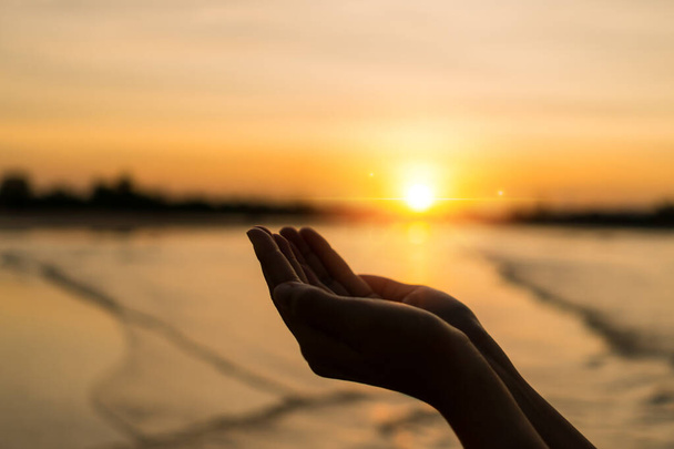 Frau Hände legen zusammen wie beten vor der Natur verschwimmen Strand Sonnenuntergang Himmel Hintergrund. - Foto, Bild