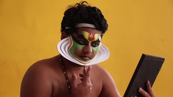 Kathakali táncos ellenőrzi az alakját chutty a tükörben.  - Felvétel, videó