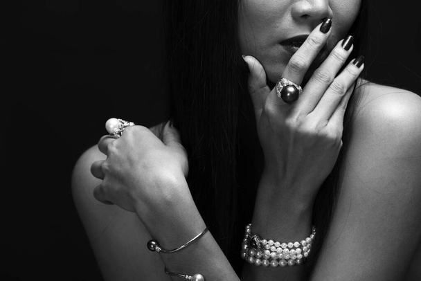 Retrato de mujer hermosa desnuda pelo largo y recto negro con accesorios collar de perlas. Chica sexy desnuda con la piel lisa en su cuerpo sobre fondo oscuro, no mostrar la cara
 - Foto, Imagen