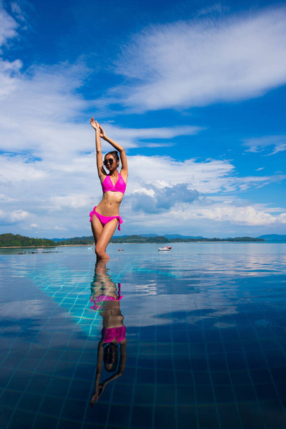 Along Side Pool with adult Mix Race Tanned Skinny Woman in sexy sensual pink bikini Swimsuit διακοπές στο Summer Island και fashion posing over blue Sky Cloud, αντίγραφο χώρου για το λογότυπο κειμένου - Φωτογραφία, εικόνα