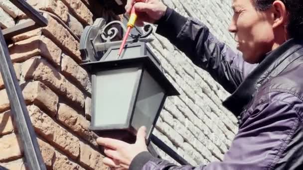 electricista de mantenimiento eléctrico cambiar la bombilla en la lámpara de pared exterior de la casa
 - Metraje, vídeo
