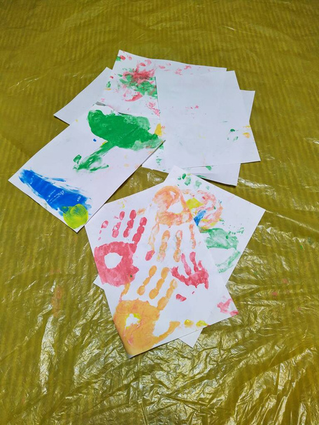 Білі папери з барвистими відбитками рук на олійній тканині
 - Фото, зображення
