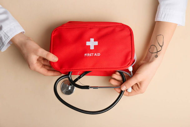 Hands of doctor with stethoscope and first aid kit on color background - Fotó, kép