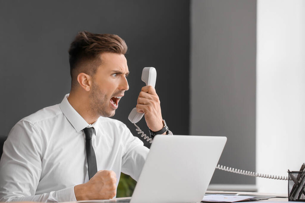 Uomo d'affari arrabbiato che parla per telefono in ufficio
 - Foto, immagini