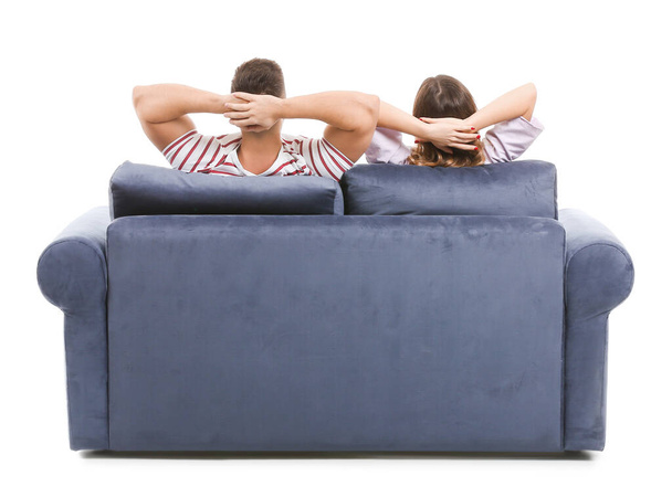 Jovem casal sentado no sofá contra fundo branco, visão traseira
 - Foto, Imagem